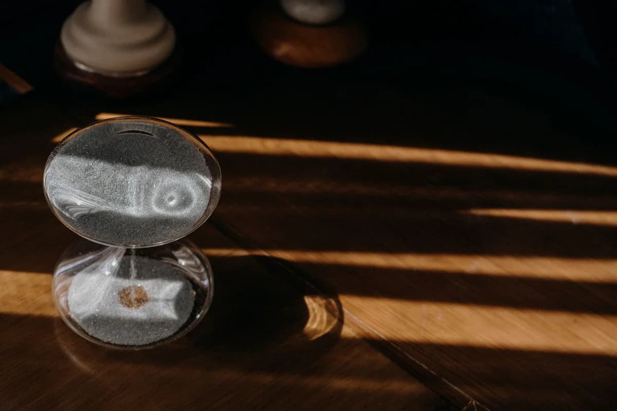 Peaceful sand timer casting shadows on a wooden table in warm morning sunlight.