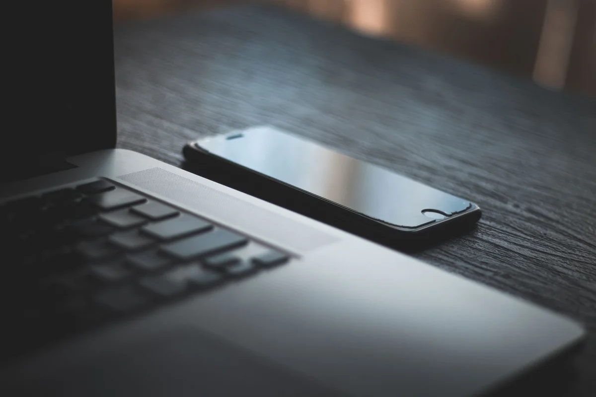 Modern laptop and smartphone on a textured wooden desk, capturing the essence of contemporary technology.