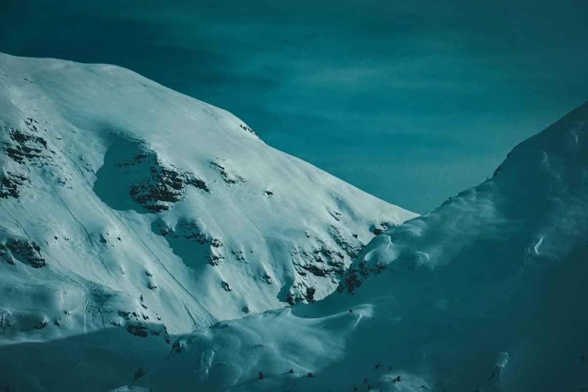 Mountainous terrain covered with snow located under cloudy sky in cold winter day