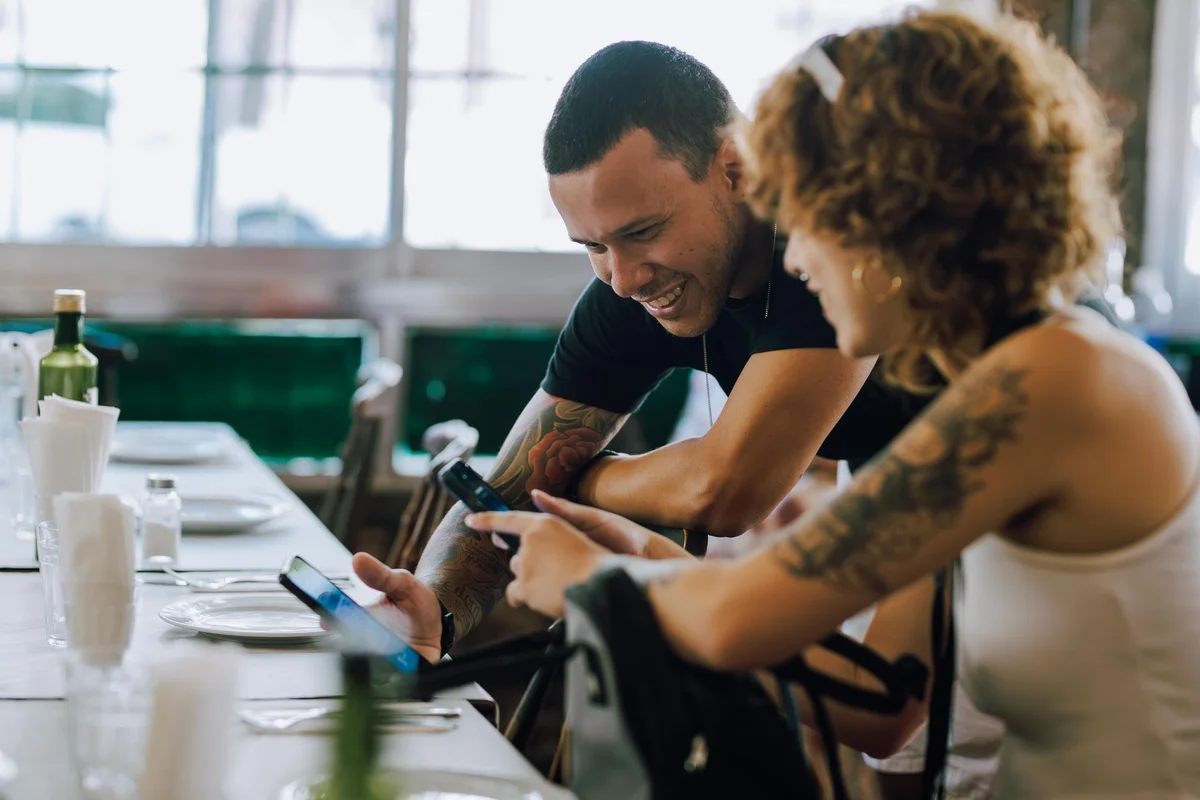 A couple sharing a moment while using smartphones at a cozy café in Buenos Aires.