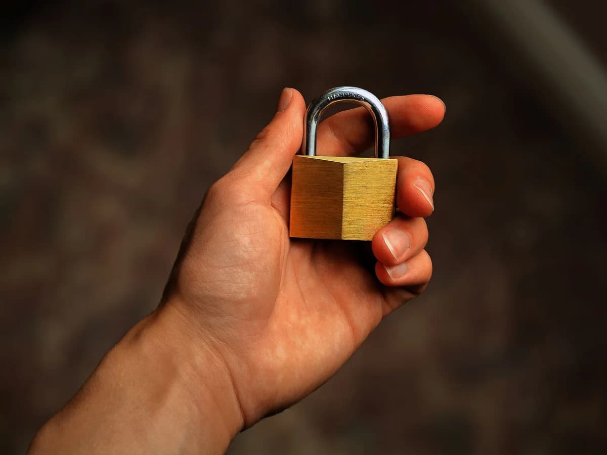 Hand holding a brass padlock, symbolizing security and protection