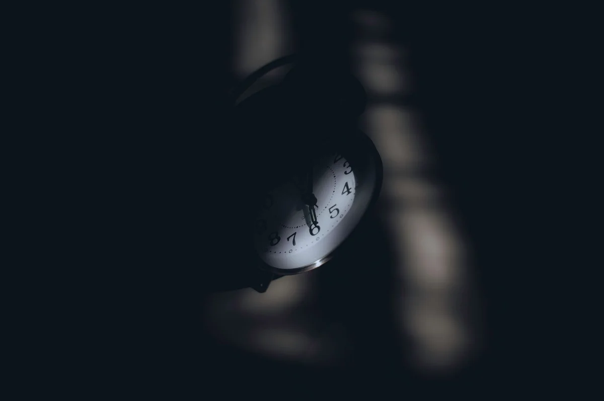 A dimly lit analog clock casting shadows, evoking a sense of mystery and time passage.