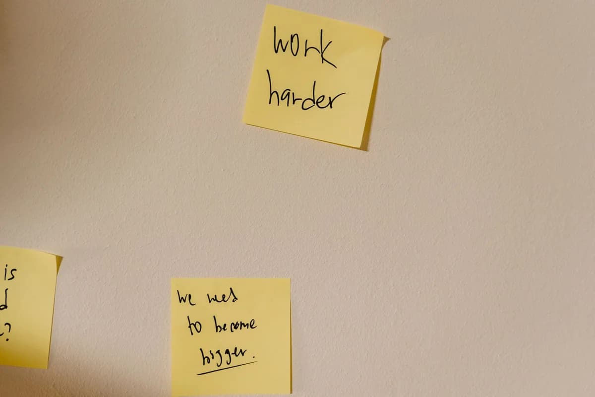 Yellow sticky notes with motivational phrases posted on a white wall, inspiring action.