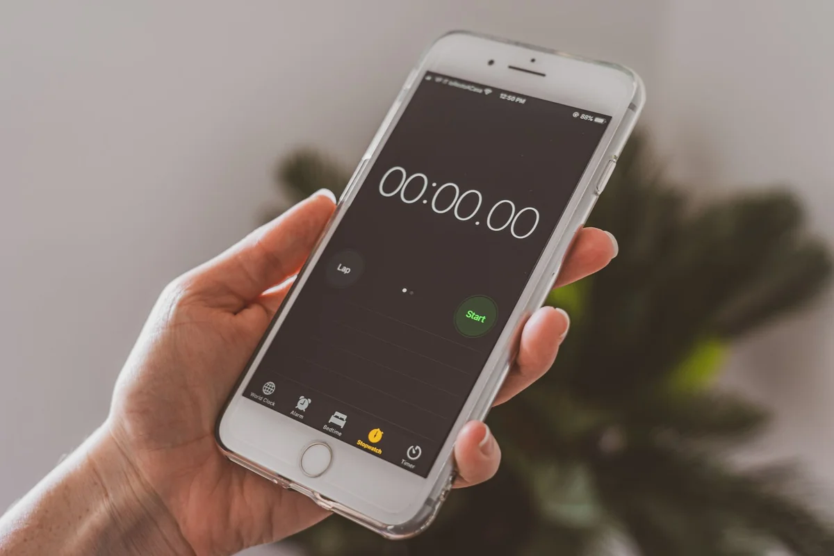 Smartphone held in hand displaying a stopwatch timer app.