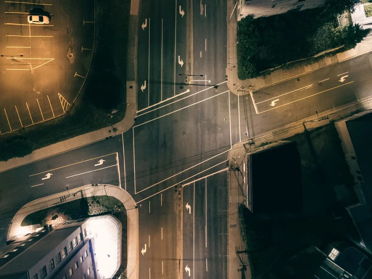High-angle shot of a deserted city intersection illuminated by street lights at night.