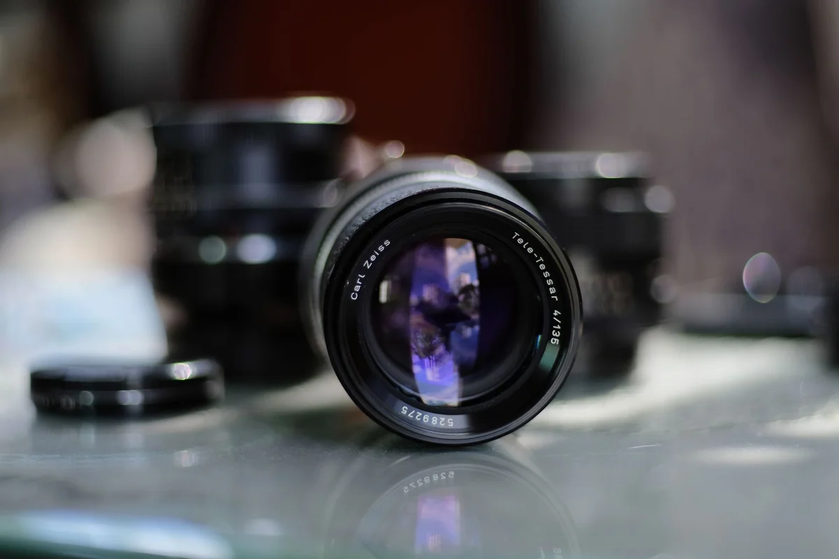 Detailed close-up of a Carl Zeiss Tele-Tessar camera lens with blurred background.