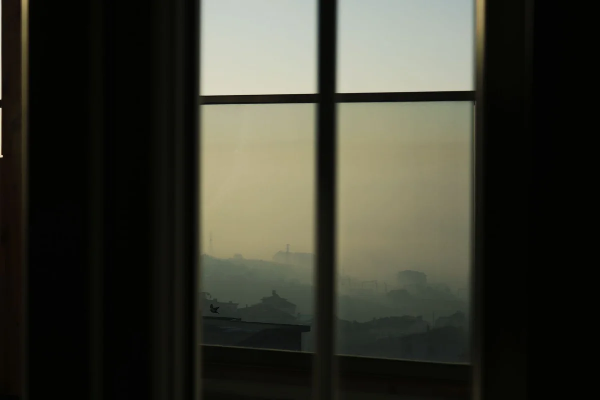 A calming view of fog-covered mountains seen through a window at dawn, creating a serene atmosphere.