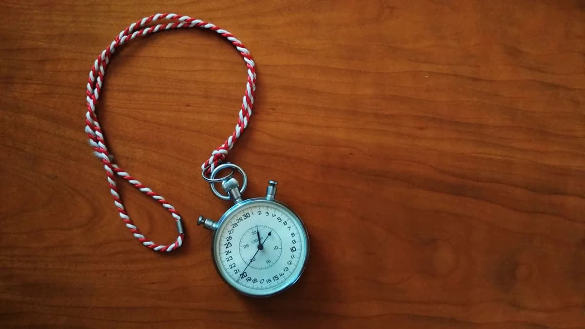 Close-up shot of an antique stopwatch with rope on wooden table.