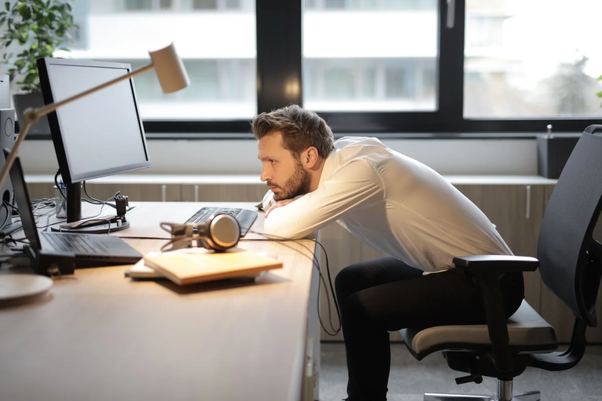 Person resting head on desk near a window, fatigued