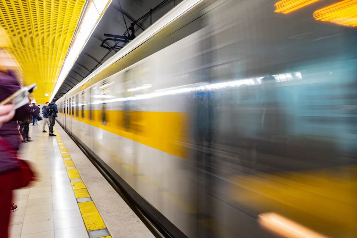 Blurred motion of a train speeding through a vibrant subway platform with commuters.