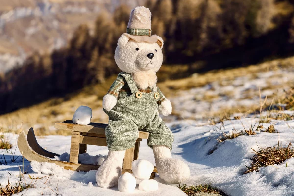 Cute plush teddy bear on a snowy sled in winter landscape.
